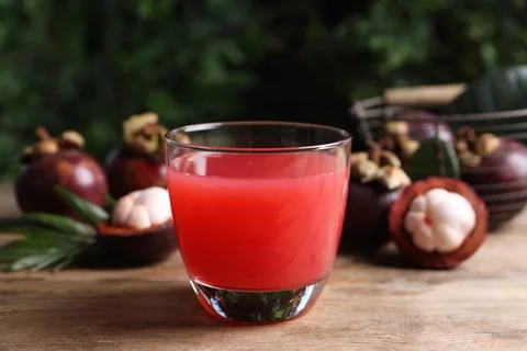 Delicious mangosteen juice in glass on wooden table Stock Photos