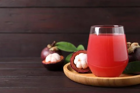Delicious mangosteen juice in glass on wooden table. Space for text Stock Photos