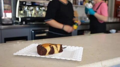 A delicious marbled cake slice rests on a white patterned plate in a cafe w.. 스톡 사진