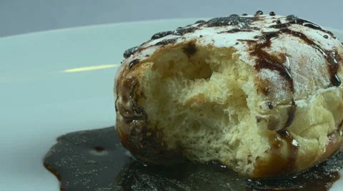 Delicious melted chocolate syrup covering a bitten donut in slow motion Stock Footage 59666632