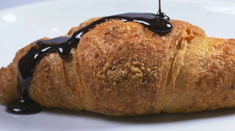 Delicious melted chocolate syrup pouring over a croissant in slow motion Stock Footage 59666078