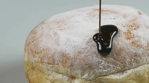 Delicious melted chocolate syrup pouring over a donut in slow motion Stock Footage 59666506