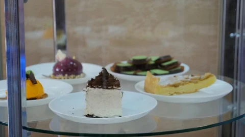 Delicious mini cakes on plates spin in glass showcase. Vitrine with mini cakes. Stock Footage 105646602