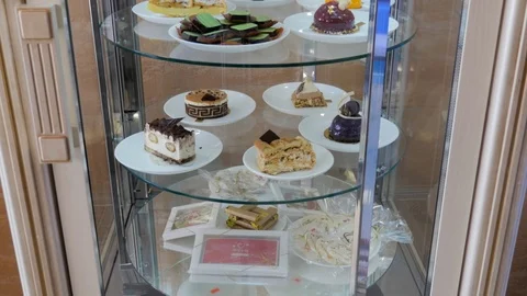 Delicious mini cakes on plates spin in glass showcase. Vitrine with mini cakes. Stock Footage 106462262