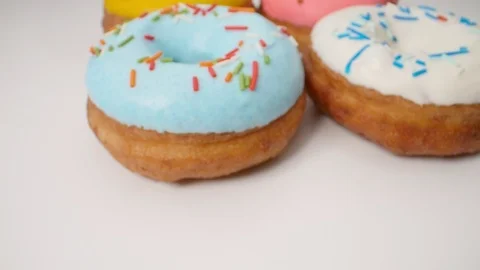 Delicious multi-colored donuts on a white background. Smooth dolly motion Stock Footage 112685510