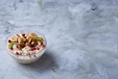 Delicious oatmeal porrige with fruits in glass bowl over white textured Stock Photos