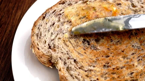 Delicious orange marmalade being spread on healthy whole wheat toast in slow Stock Footage 46906840