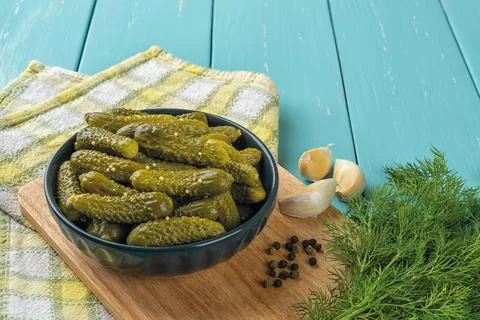 Delicious pickled cornichons in a dark ceramic bowl, garlic, pepper and dill Stock Photos