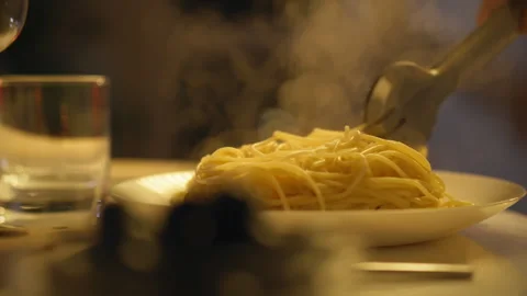 Delicious plate of steaming pasta served at a cozy dinner table in the eveni Stock Footage 295128654