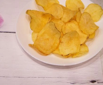 Delicious potato chips round shape, on a white plate on the background of a l Foto stock