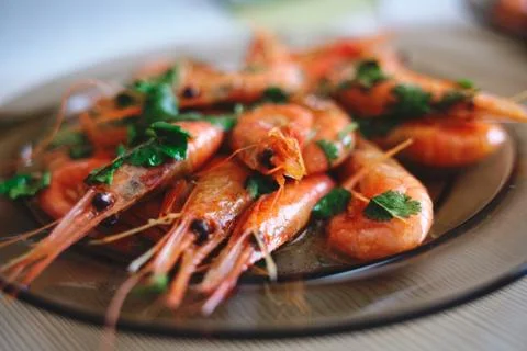 Delicious prawns with coriander in a plate on the table. Fresh seafood dish c Stock Photos