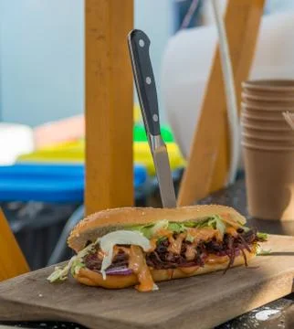 Delicious pulled pork sandwich served with a knife on a wooden plate. Stock Photos