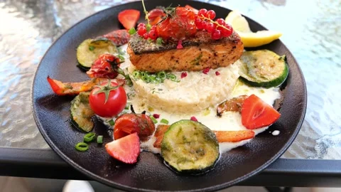 Delicious risotto with baked grilled salmon steak with berries and vegetables Stock Footage 159608454
