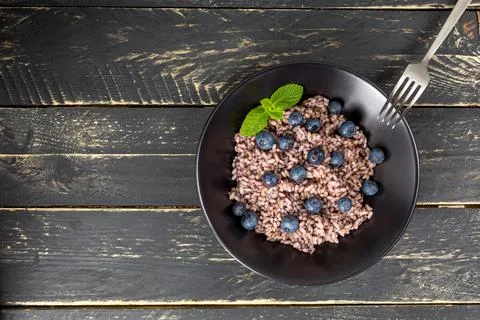 Delicious risotto with blueberries served on dark wooden table, flat lay Stock Photos