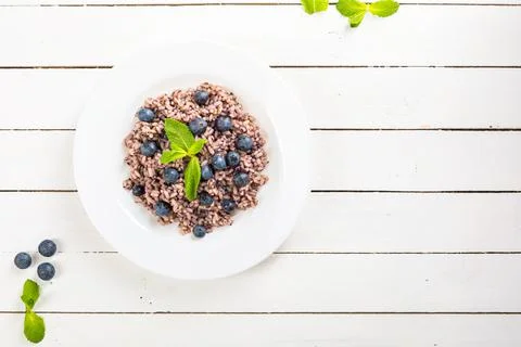 Delicious risotto with blueberries served on white wooden table, flat lay Stock Photos