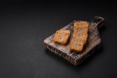 Delicious salted rectangular wheat croutons with salt and spices on a dark co Stockfoto's