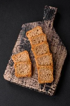 Delicious salted rectangular wheat croutons with salt and spices on a dark co Stockfoto's