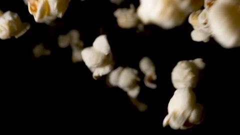 Delicious salty popcorn is falling down on black background in slowmo. Video stock 153579253