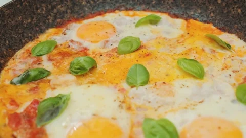 Delicious scrambled eggs with tomatoes and basil in a frying pan Stock Footage 249600523