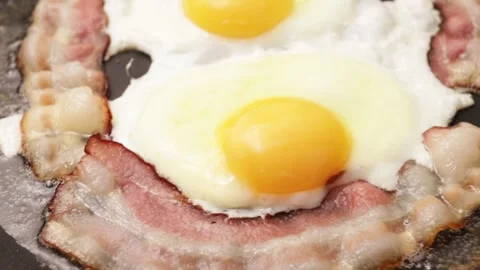 A delicious slice of bacon and fried eggs cooked to perfection in a skillet.. Stock Footage 252021263
