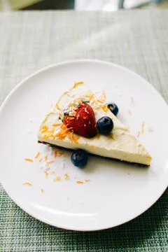 Delicious slice of mango cake with berries on a white plate in a restaurant Stock Photos