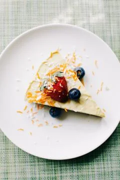 Delicious slice of mango cake with berries on a white plate in a restaurant Stock Photos