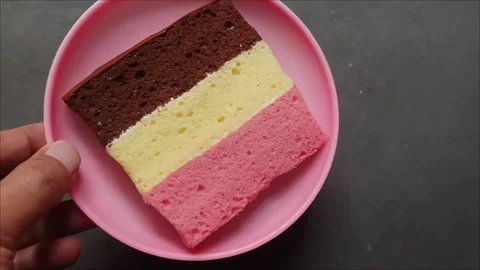 A delicious slice of Neapolitan cake on a pink plate Stock Footage 323579663