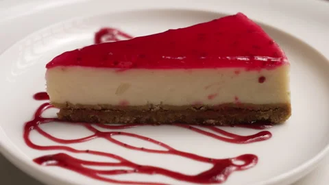 Delicious slice of raspberry cheesecake rotating on a white plate Stock Footage 333594112