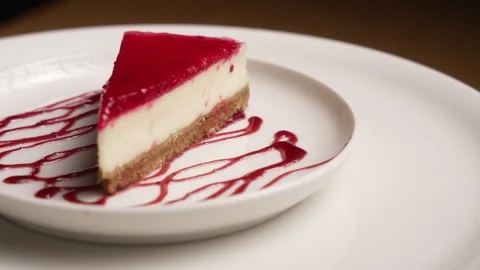 Delicious slice of raspberry cheesecake rotating on a white plate 库存影片 333594227