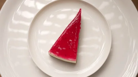 Delicious slice of raspberry cheesecake spinning on a white plate Stock Footage 333458308