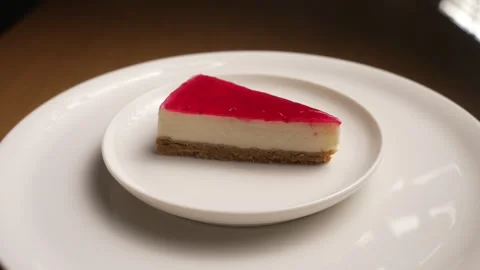 Delicious slice of raspberry cheesecake spinning on a white plate Stock Footage 333458546