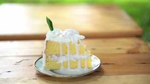 Delicious slice of yellow cake with whipped cream and decorative green leaf.. Stock Footage 327828383