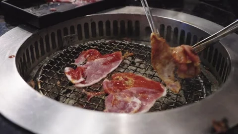 Delicious slices of marinated meat grilling on a round metal mesh over hot .. Stock Footage 337332932