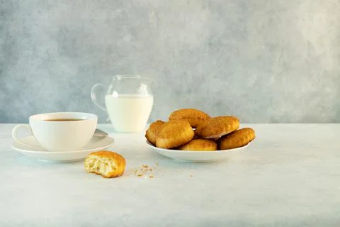 Delicious snack: a cup of black tea with milk and a plate of cookies on a gra Stock Photos