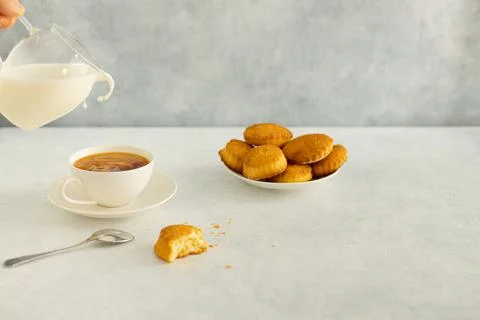 Delicious snack: a cup of black tea with milk and a plate of cookies on a gra Stock Photos