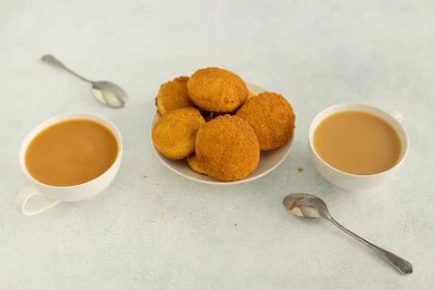 Delicious snack: two cups of black tea with milk and a plate of cookies on a Stock Photos