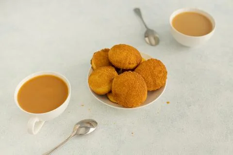 Delicious snack: two cups of black tea with milk and a plate of cookies on a Stock Photos