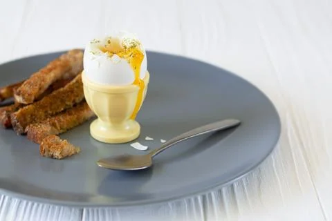 Delicious soft boiled egg in an eggcup with toasted bread for breakfast Stock Photos