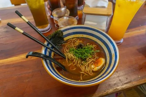 Delicious spicy ramen bowl with egg and chopsticks served on a wooden table Foto stock