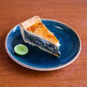 Delicious spinach quiche slice with lime on ceramic plate Stock Photos