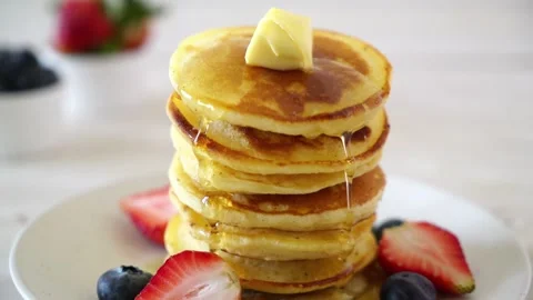 Delicious stack of golden pancakes drizzled with syrup and topped with butt.. Stock Footage 337404531