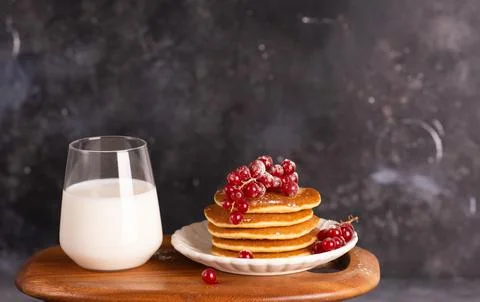Delicious stack of pancakes with fresh berries and a glass with milk. Stock Photos
