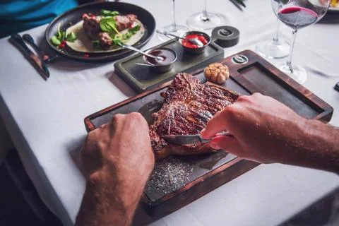 Delicious steak on the table that cuts a man Stock Photos
