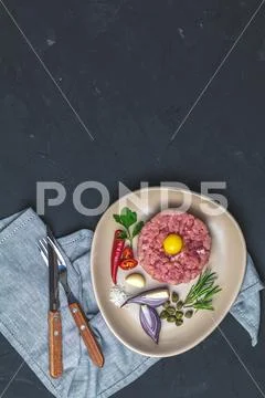 Delicious steak tartare with yolk and ingredients on ceramic plate Stock Photos
