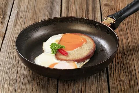 Delicious sunny side up egg with ham in pan Stock Photos