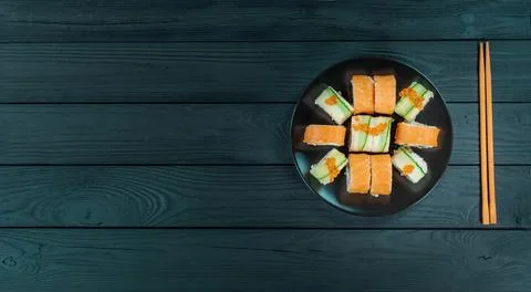 Delicious sushi on a black plate, lie on a black wooden board. Stock Photos