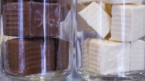 Delicious sweet candy in white and black chocolate glaze in a glass jar. HD Stock Footage 85773829
