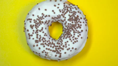 Delicious sweet donut quickly rotating on a plate. Top view. Yellow background. Stock Footage 87992356