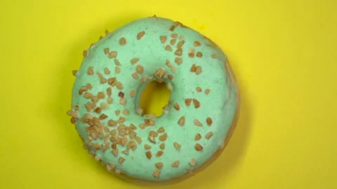Delicious sweet donut quickly rotating on a plate. Top view. Yellow background. Stock Footage 87994146