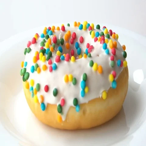 Delicious sweet donut with white icing rotating on a white plate. White Stock Footage